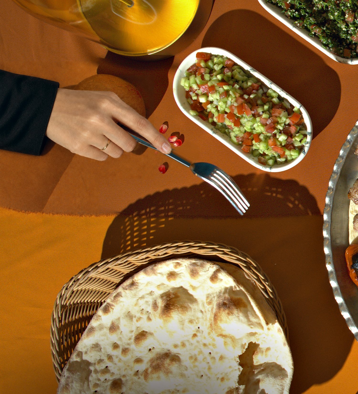 Shirazi Salad and bread on the orange cloth, a hand with a fork